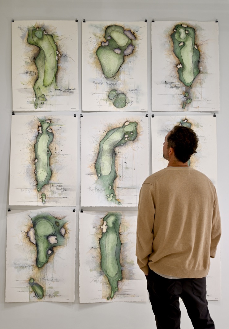Artist Mark Rivard studying a gallery wall of his nine Prairie Dunes hole paintings